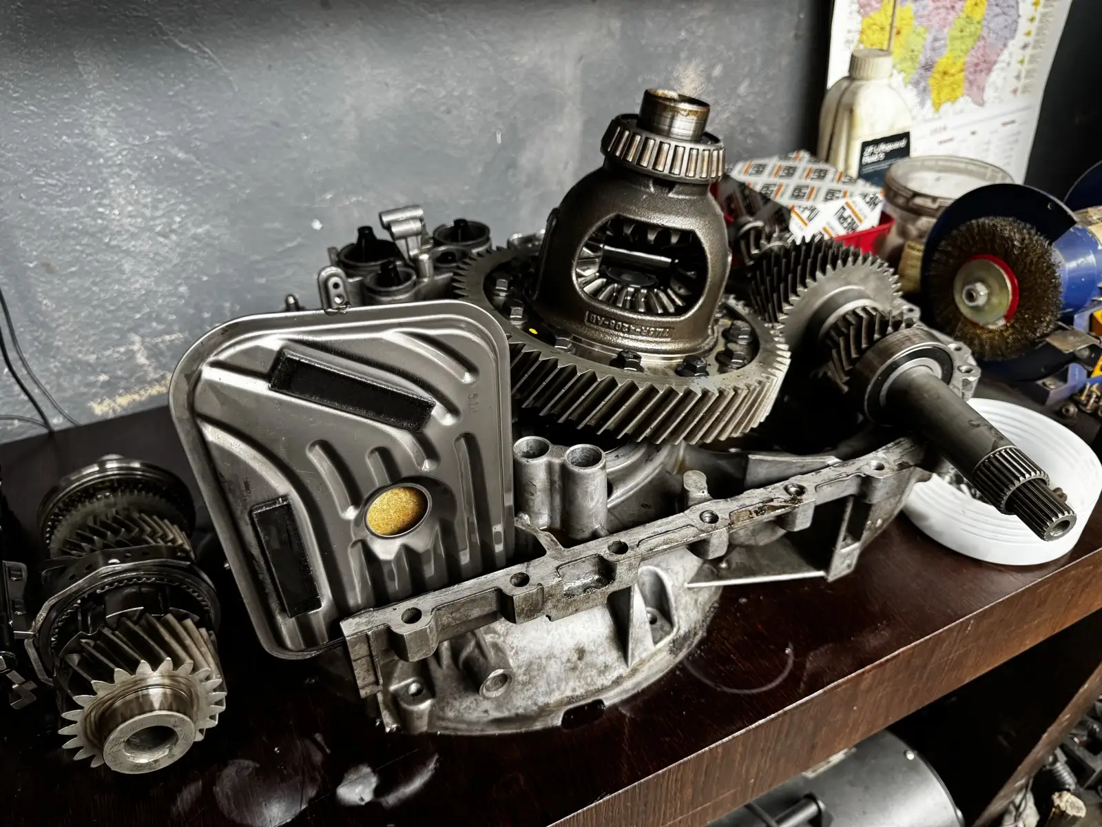 Rozłożona skrzynia biegów z widocznym mechanizmem różnicowym i filtrem hydraulicznym na stole warsztatowym