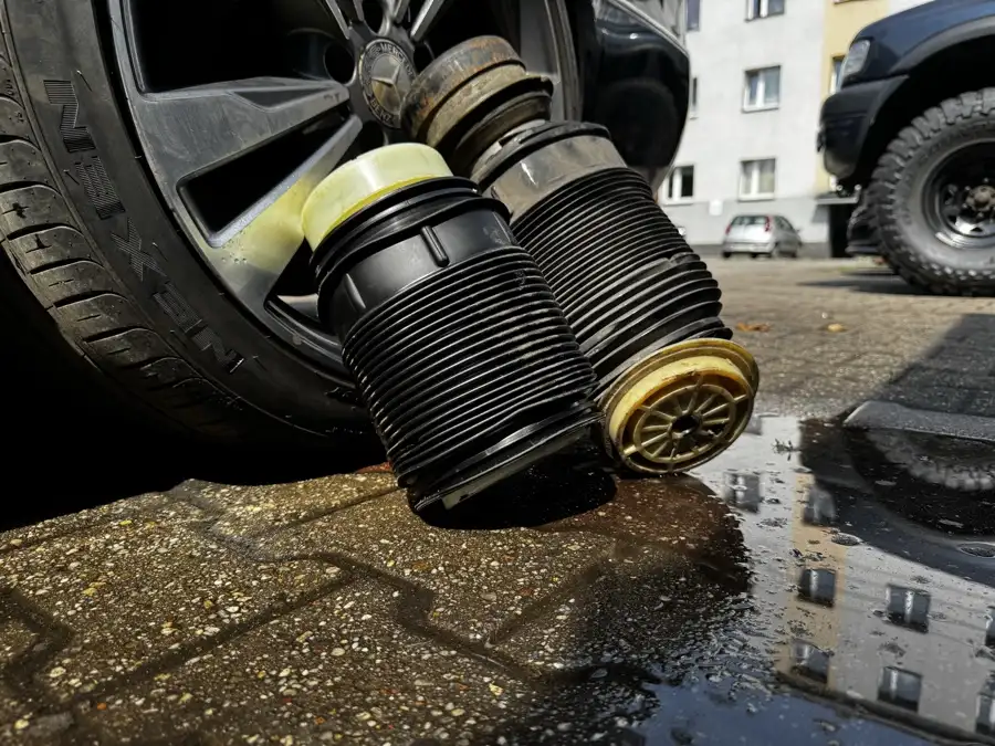 Dwa uszkodzone miechy zawieszenia pneumatycznego obok koła Mercedesa przed warsztatem